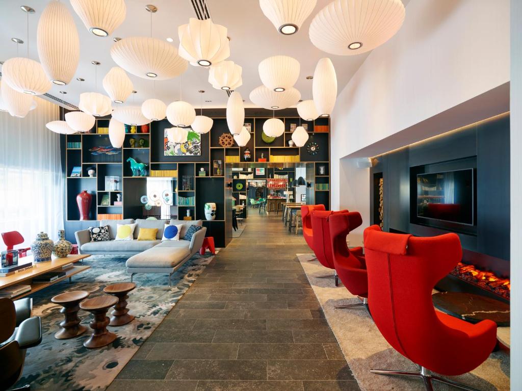 un hall d'un hôtel avec des chaises et des tables rouges dans l'établissement citizenM Paris Gare de Lyon, à Paris