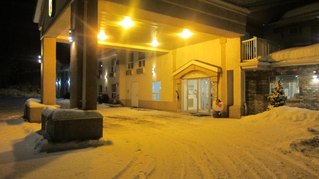 a snow covered yard in front of a house at Super 8 by Wyndham Revelstoke BC in Revelstoke