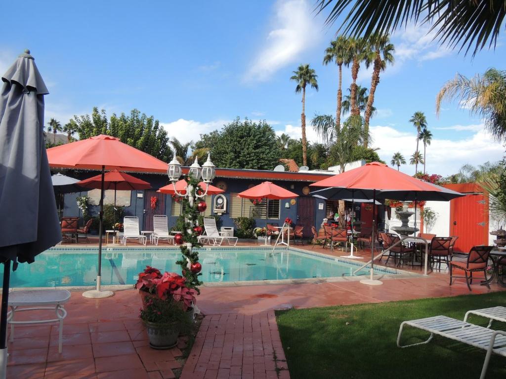 uma piscina com mesas e guarda-sóis e um restaurante em Casa Larrea Inn em Palm Desert