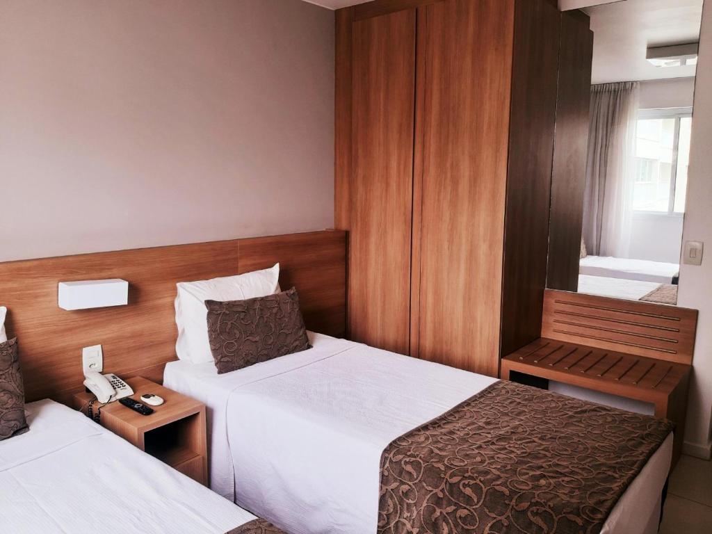 a hotel room with two beds and a telephone at Apê na Barra, ao lado do Parque Olímpico, Jeunesse Arena, ar, wi fi, tv a cabo, microondas in Rio de Janeiro