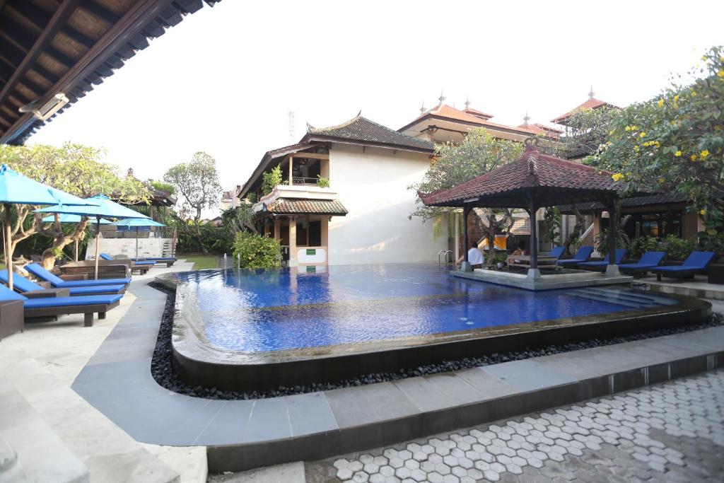 a pool in the middle of a building with a fountain at Fat Yogi Cottages in Kuta