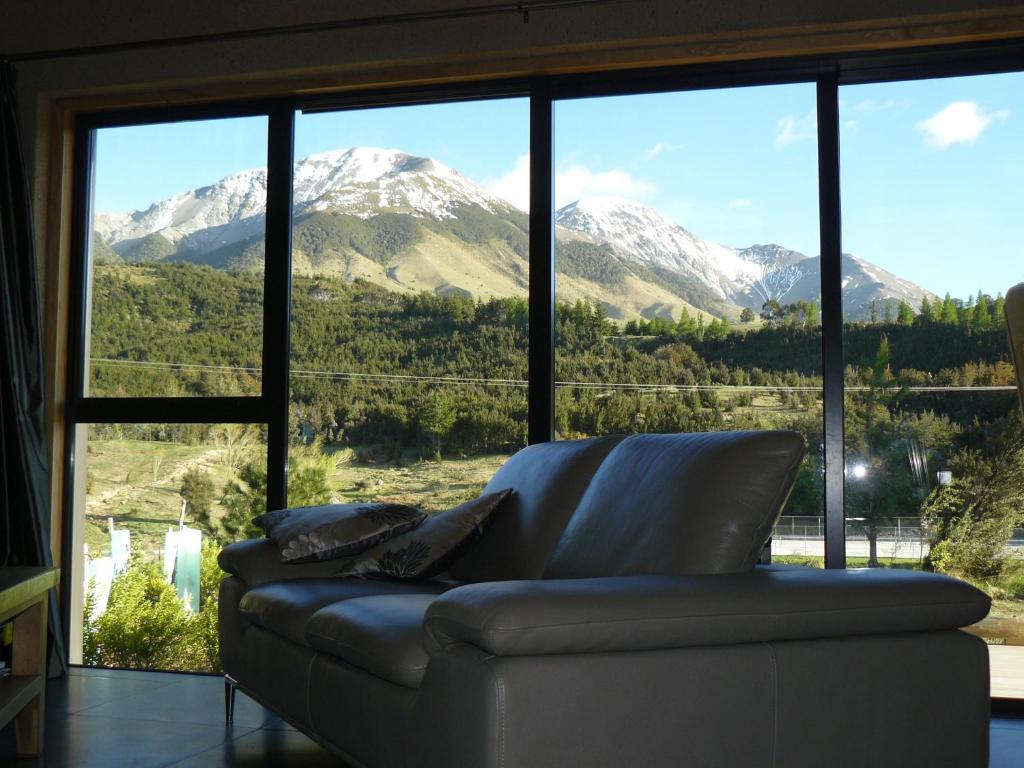 a couch in front of a large window with snow covered mountains at Mt Lyford Holiday Homes in Mt Lyford