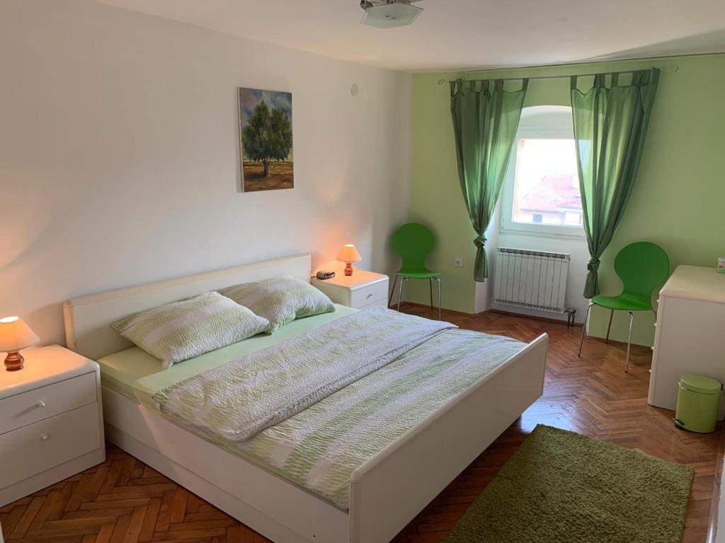 een slaapkamer met een bed en 2 groene stoelen bij Kuća za odmor City Oasis in Rijeka