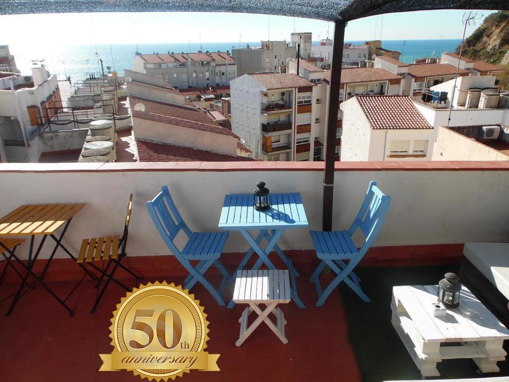 a balcony with a table and chairs and a anniversary sign at Hostal La Lluna in Arenys de Mar