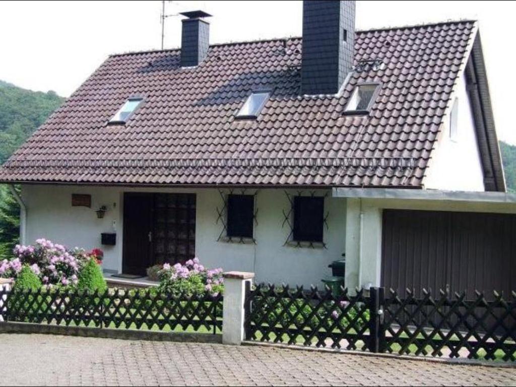een wit huis met een zwart dak en een hek bij Ferienwohnung Waldruhe in Hessisch Oldendorf