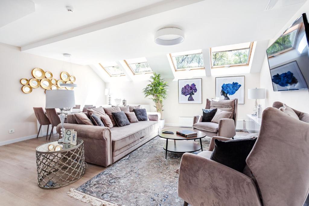 uma sala de estar com um sofá, cadeiras e janelas em Luxury for everyone - Hills Park Lux Apartments 1 em Vilnius
