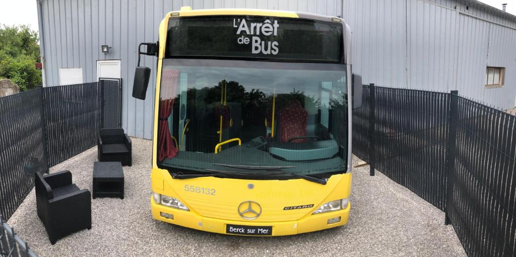 un bus jaune garé à côté d'un bâtiment dans l'établissement L Arrêt de Bus Insolite & SPA, à Berck-sur-Mer