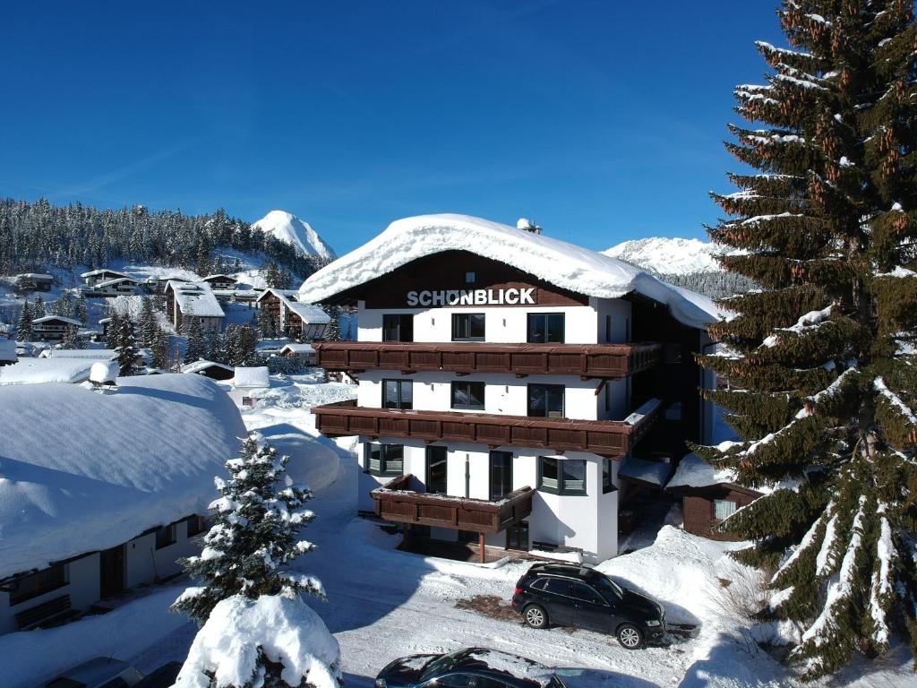 pokryty śniegiem budynek z samochodem zaparkowanym przed budynkiem w obiekcie Haus Schönblick w mieście Seefeld in Tirol