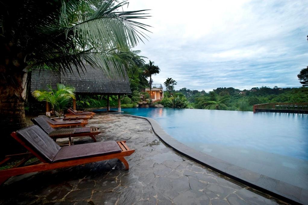 a swimming pool with lounge chairs next to a river at SanGria Resort And Spa in Lembang
