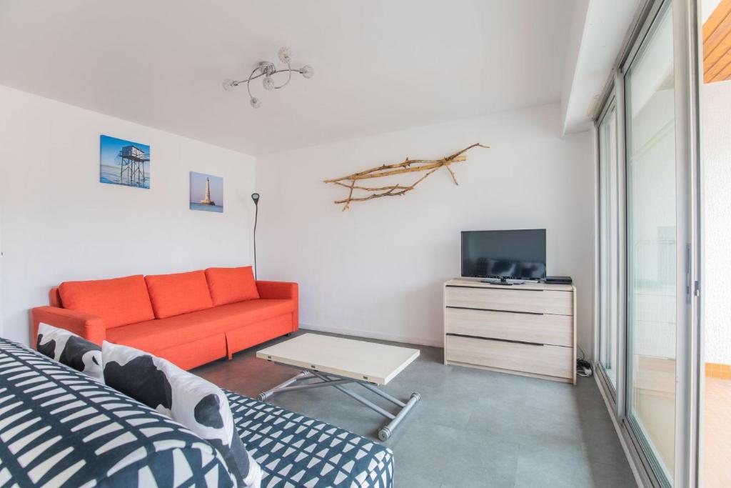 Un dormitorio con una cama, un sofá y un televisor. en Le coeur de Royan studio 2 étoiles, en Royan