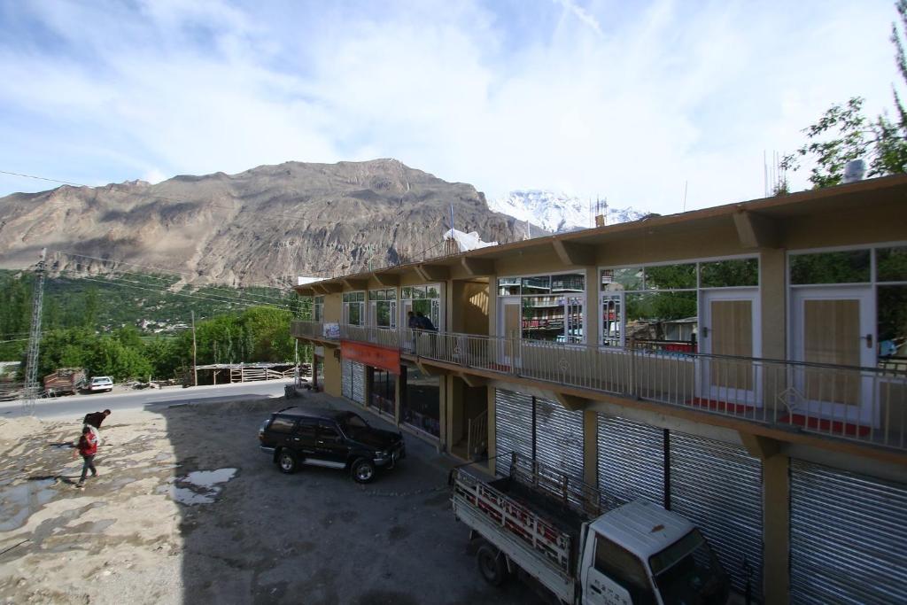 a woman standing in front of a building with a mountain at Hotel Oshin Hunza in Alīābād
