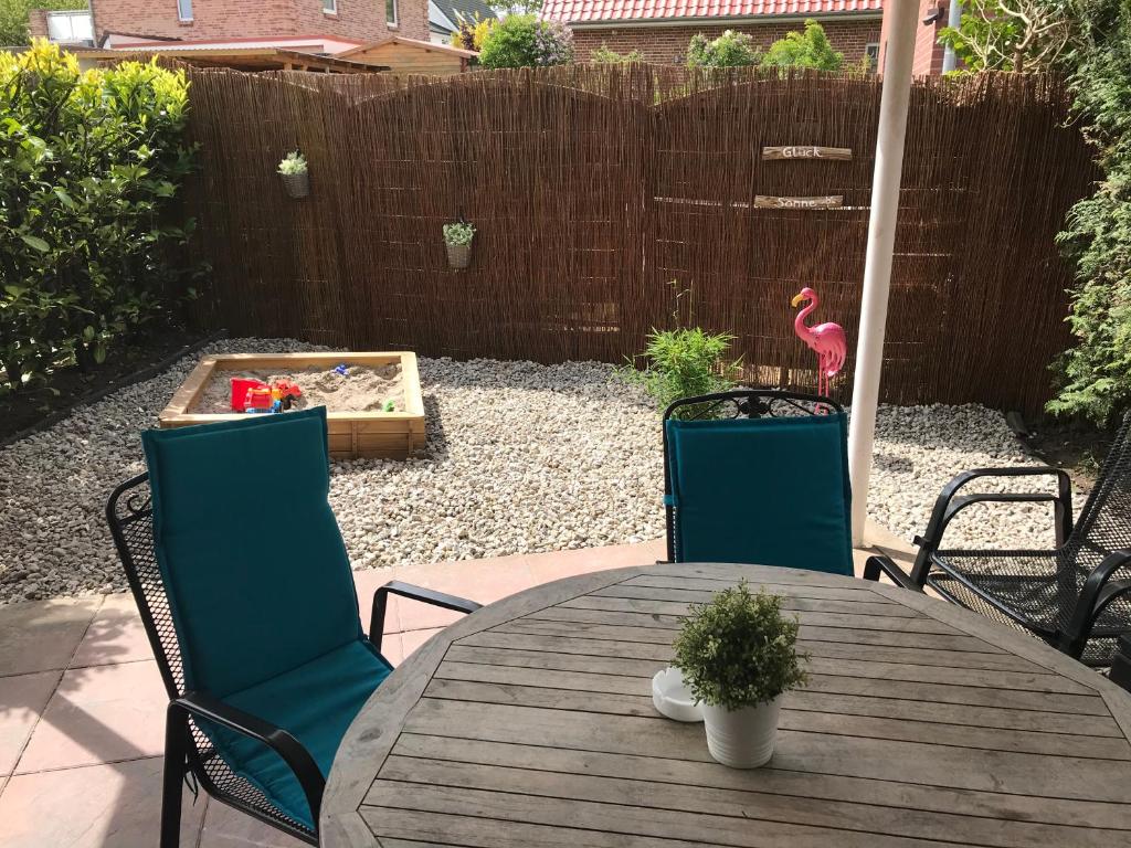 a wooden table with chairs and a pink flamingo in a backyard at Kleine Sonne in Grömitz