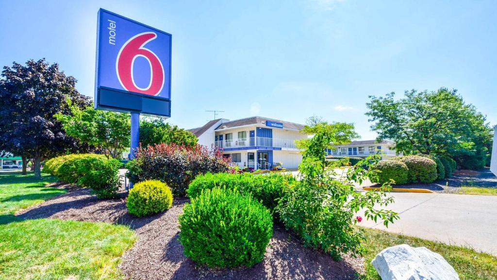 Motel 6-Windsor Locks, CT - Hartford في ويندسور لوكس: لافته لفندق فيه شجيرات امام مبنى