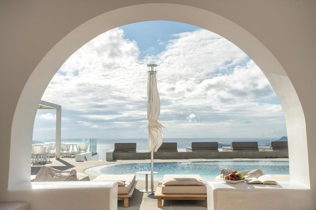 an archway over a swimming pool with a view of the ocean at Lilium Hotel Santorini in Fira
