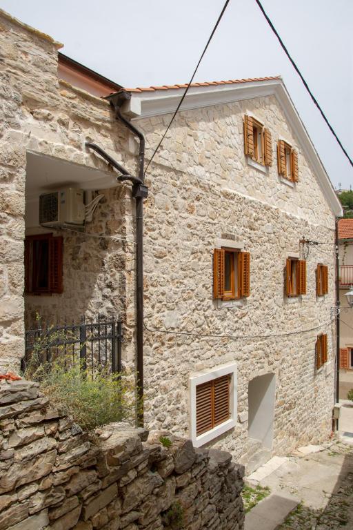 a stone house with wooden windows and a stone wall at Krka Waterfalls in Skradin