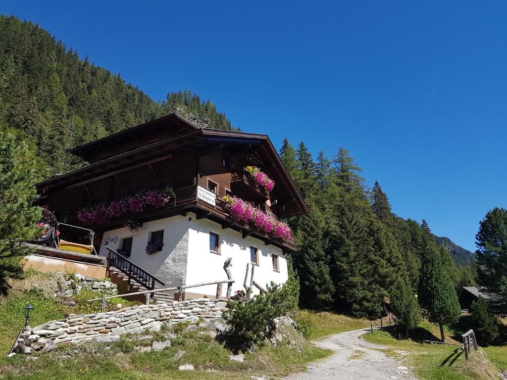 a house with flowers on the balcony on a mountain at Pension Fürhapter mit Bio- Bauernhof in Sankt Jakob in Defereggen