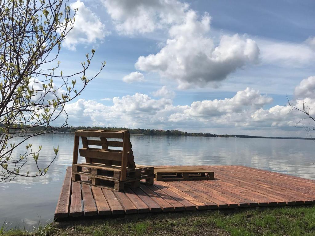 un banco sentado en un muelle en un lago en Domek nad samym brzegiem jeziora z prywatną "4-You" en Mikołajki