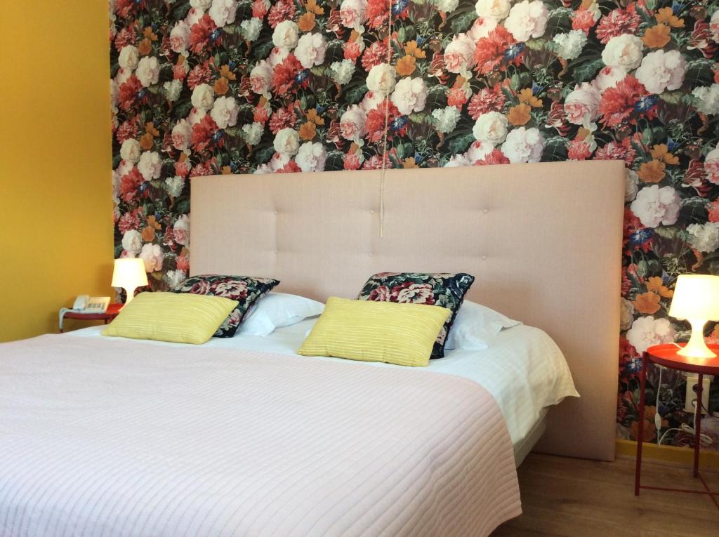 a bedroom with two beds with a floral wallpaper at Boutique Hotel Butler in Zuienkerke