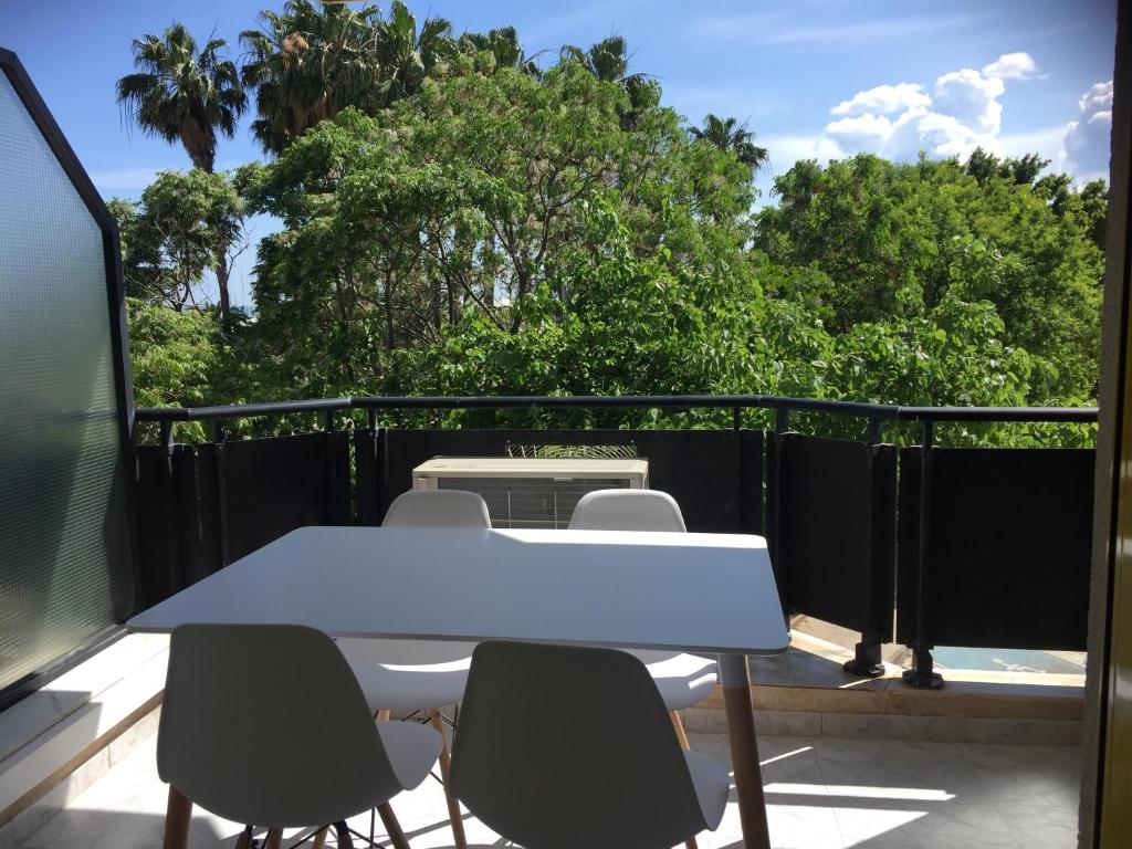 une table et des chaises blanches sur un balcon arboré dans l'établissement Apartamento delante del puerto deportivo ., à Sant Carles de la Ràpita