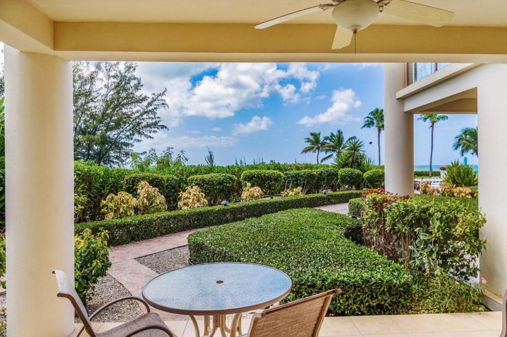 een patio met een tafel, stoelen en struiken bij Coral Gardens on Grace Bay in Grace Bay