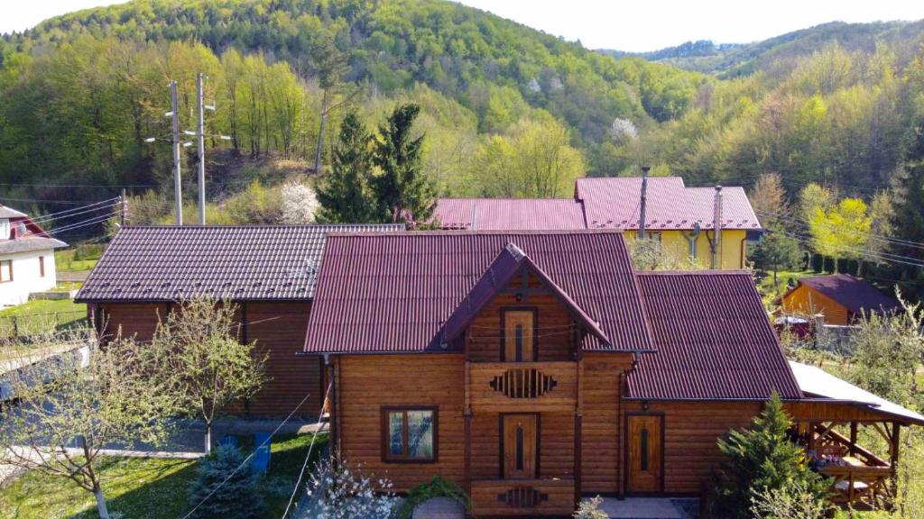 une grande maison en bois avec un toit rouge dans l'établissement Котедж "Хата Рибака", à Kossiv