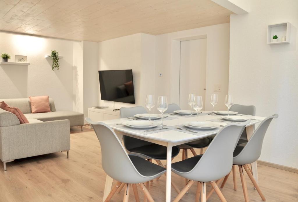 ein weißes Esszimmer mit einem weißen Tisch und Stühlen in der Unterkunft Modern Family Apartment in Interlaken Center in Interlaken