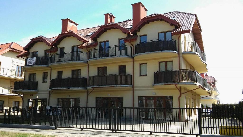 un grand bâtiment jaune avec balcon et clôture dans l'établissement Apartament Przytulny, à Karwia