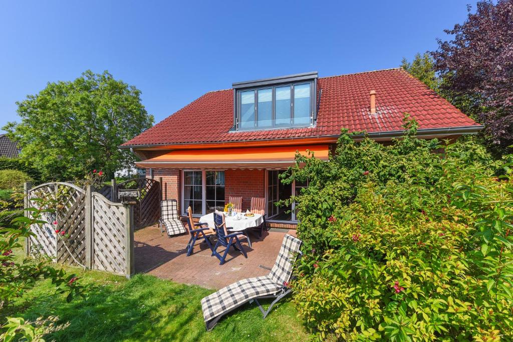 ein Haus mit einem Tisch und Stühlen im Hof in der Unterkunft Jever-Ferienhaus Gartenblick in Jever