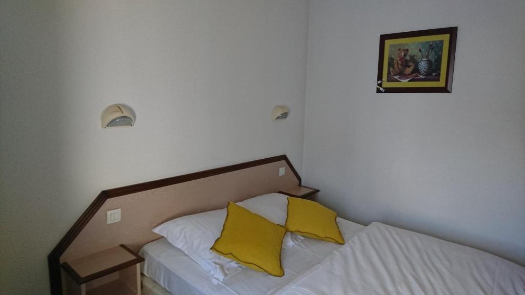 a bedroom with a bed with two yellow pillows at Hôtel Les Deux Porches in Verrières