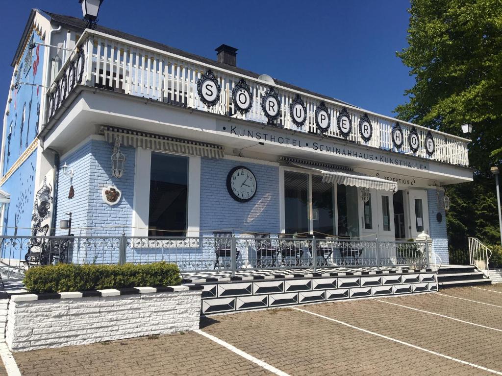 un bâtiment bleu avec une horloge sur son côté dans l'établissement Söruper Hof, à Sörup