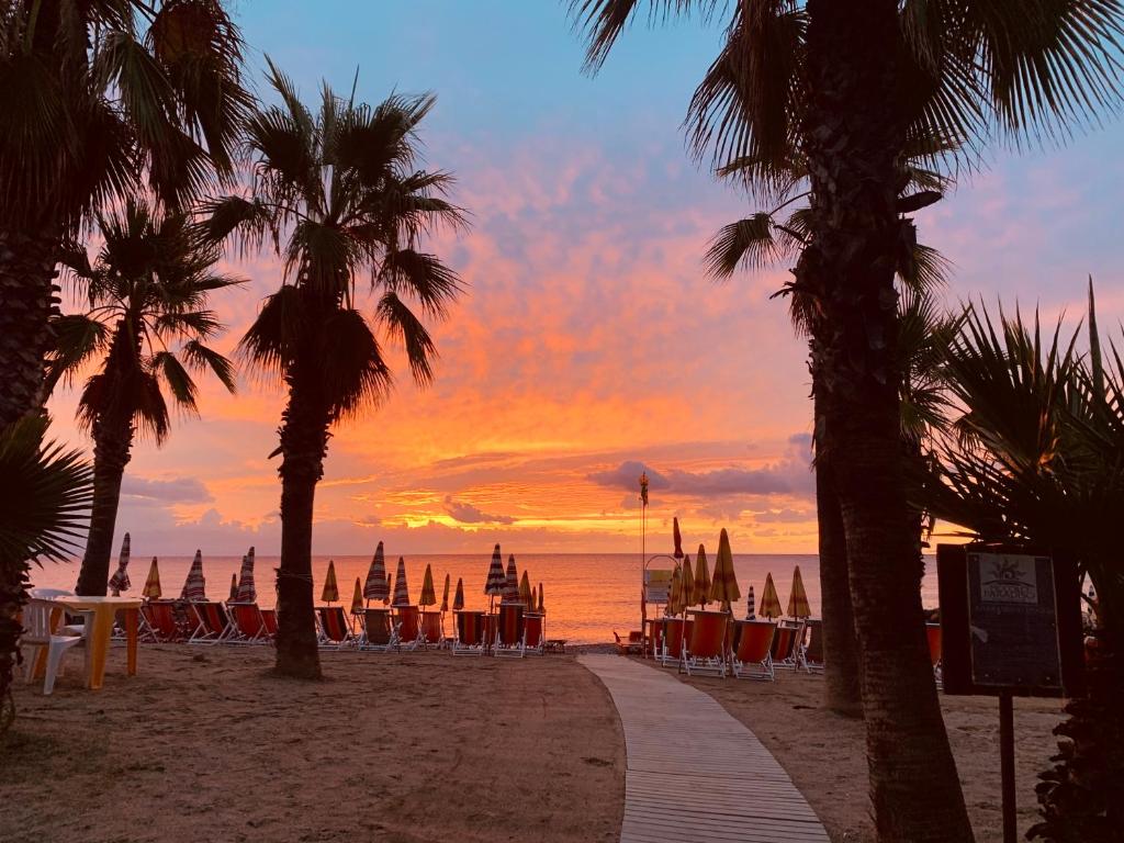 puesta de sol en la playa con sillas y sombrillas en Piccolo Paradiso, en Albenga
