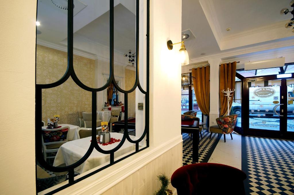 Decorative black metal partition framing cozy cafe seating, white tables, patterned wallpaper, mustard curtains.