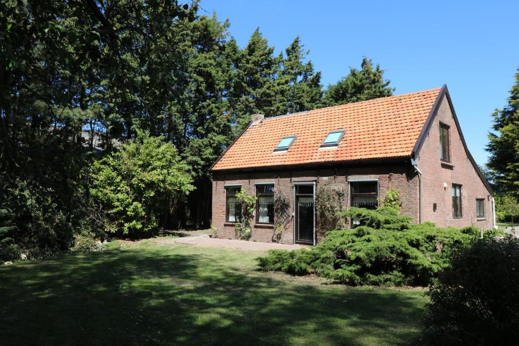 Hof Zuidvliet في Wolphaartsdijk: منزل من الطوب وسقف احمر على ساحة