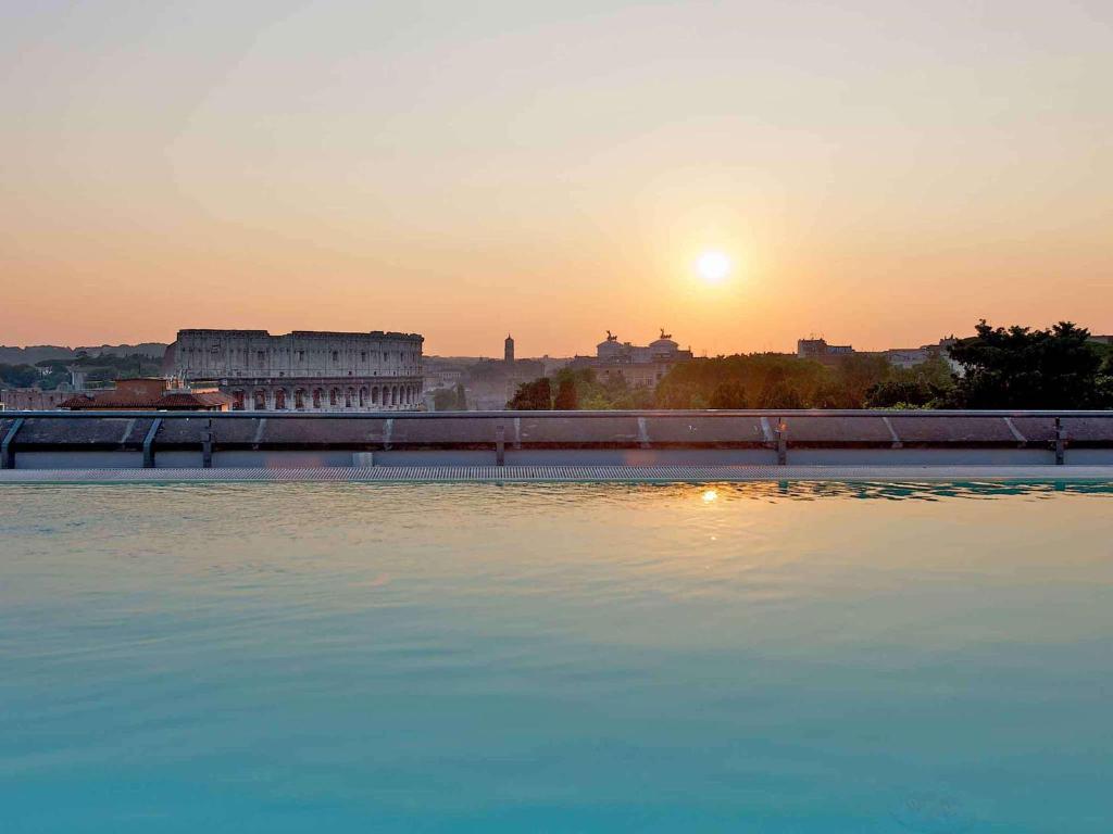 un grande bacino d'acqua con il tramonto sullo sfondo di Mercure Roma Centro Colosseo a Roma