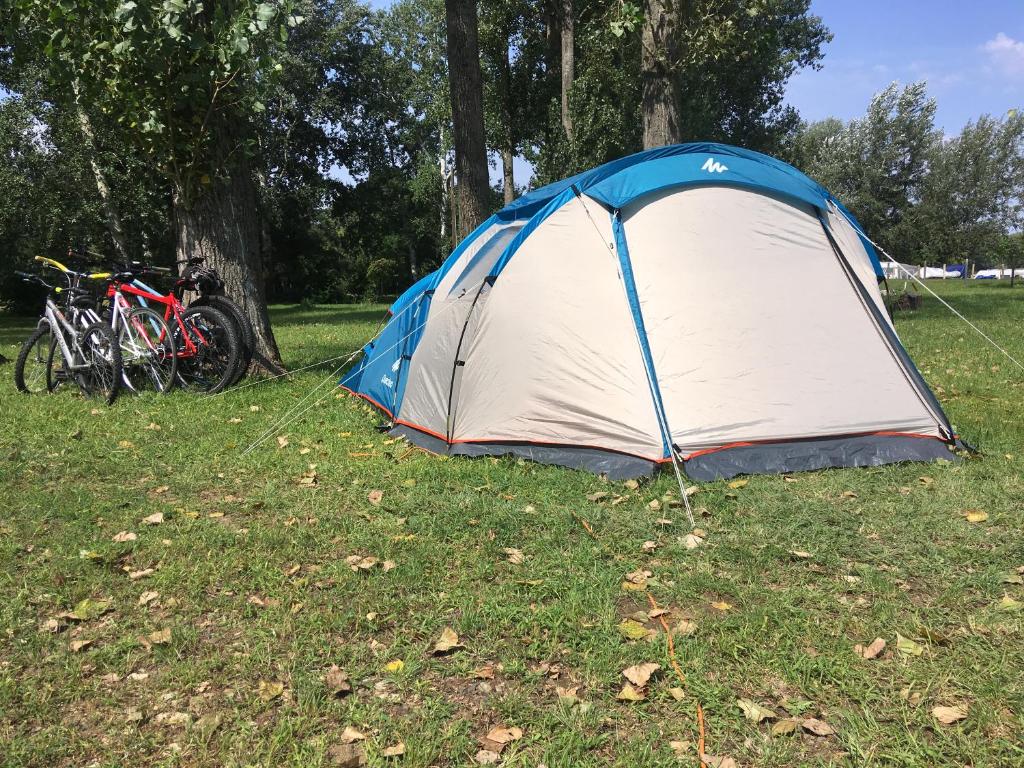 een blauwe en witte tent in een veld met fietsen bij Tóparti Camping in Tiszafüred