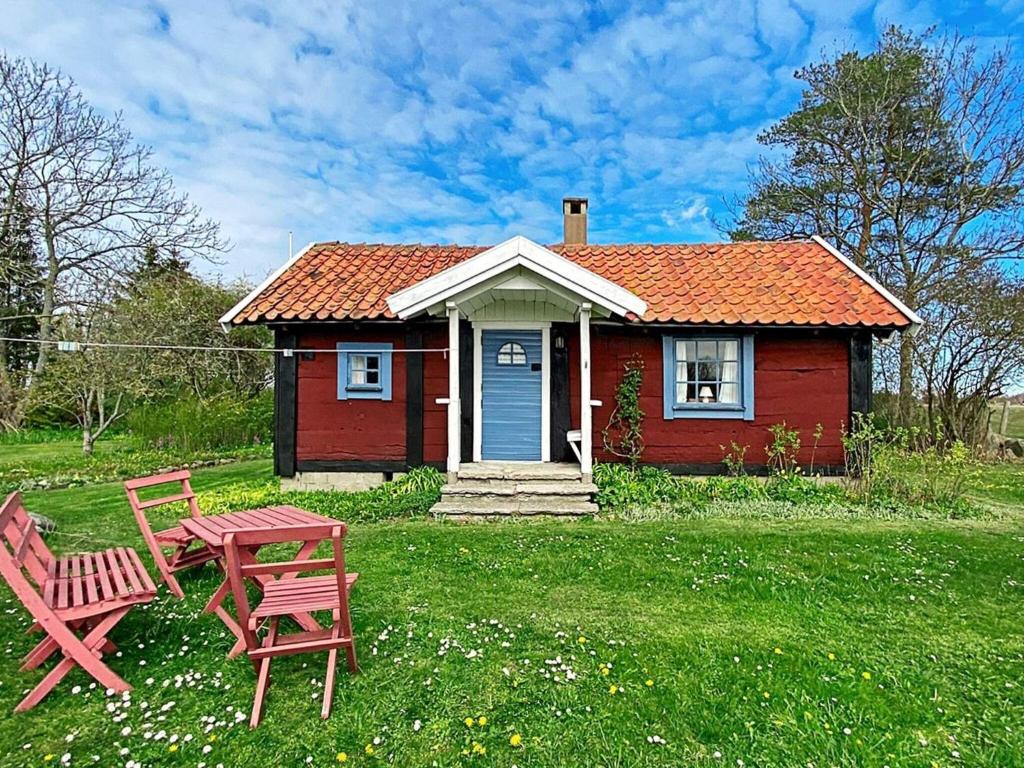 een klein rood huis met een tafel en twee stoelen bij 4 person holiday home in L TTORP in Löttorp