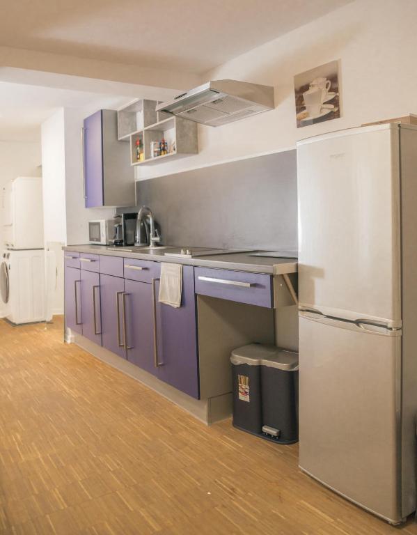 a kitchen with purple cabinets and a refrigerator at Altstadt Apartment Alisa in Düsseldorf