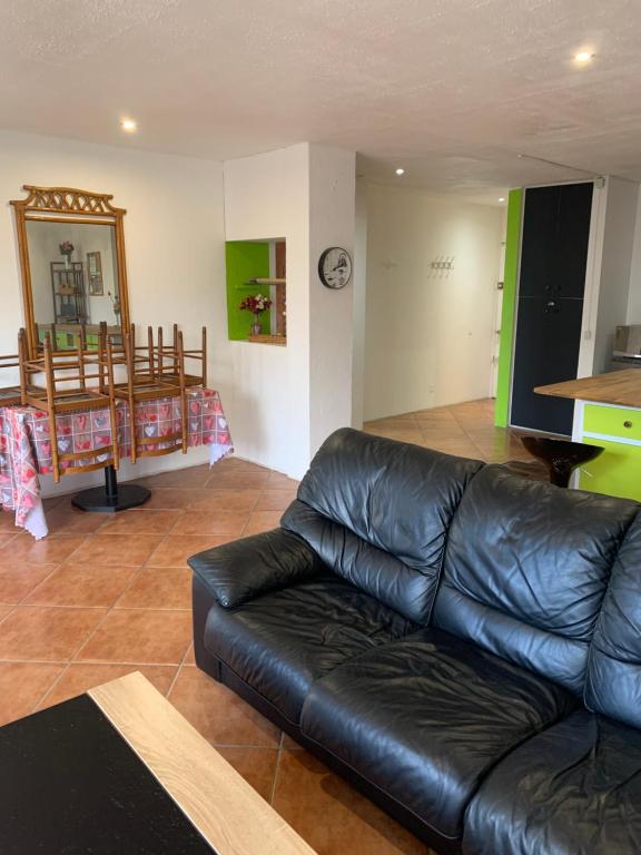 a living room with a black leather couch and a mirror at F2 Tapu in Papeete