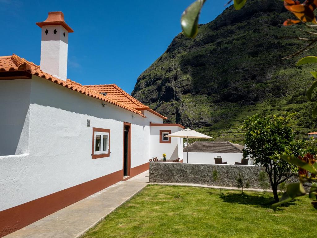 a white building with a mountain in the background at Casa do Bago in São Vicente