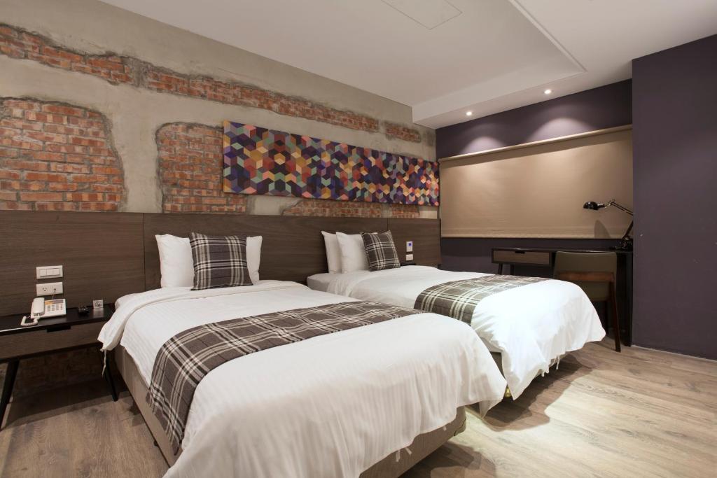 two beds in a hotel room with a brick wall at P&amp;F Hotel in Taichung