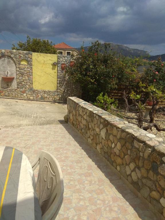 a stone wall with a bench on a patio at Philoxenia Holiday Home in Pappadhiánika