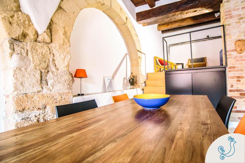 jadalnia z drewnianym stołem i kamienną ścianą w obiekcie Scuderie Reali - Loft in Castello, old town w Cagliari