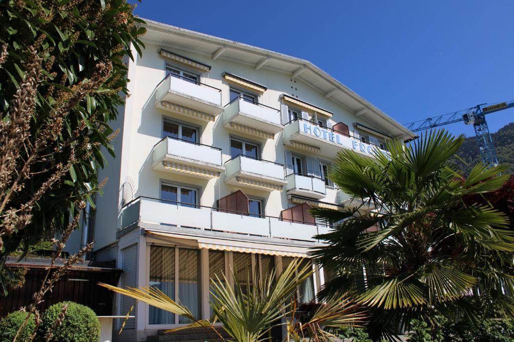 a white building with a palm tree in front of it at Garni-Hotel Frohburg - Beau Rivage Collection in Weggis