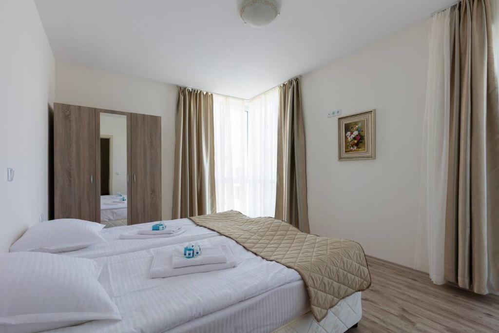 a bedroom with a white bed with a large window at Zevs Residence in Nesebar