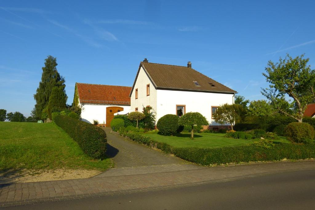 een wit huis met een zwart dak en een straat bij Ferienwohnung Eifelgold Esch in Esch