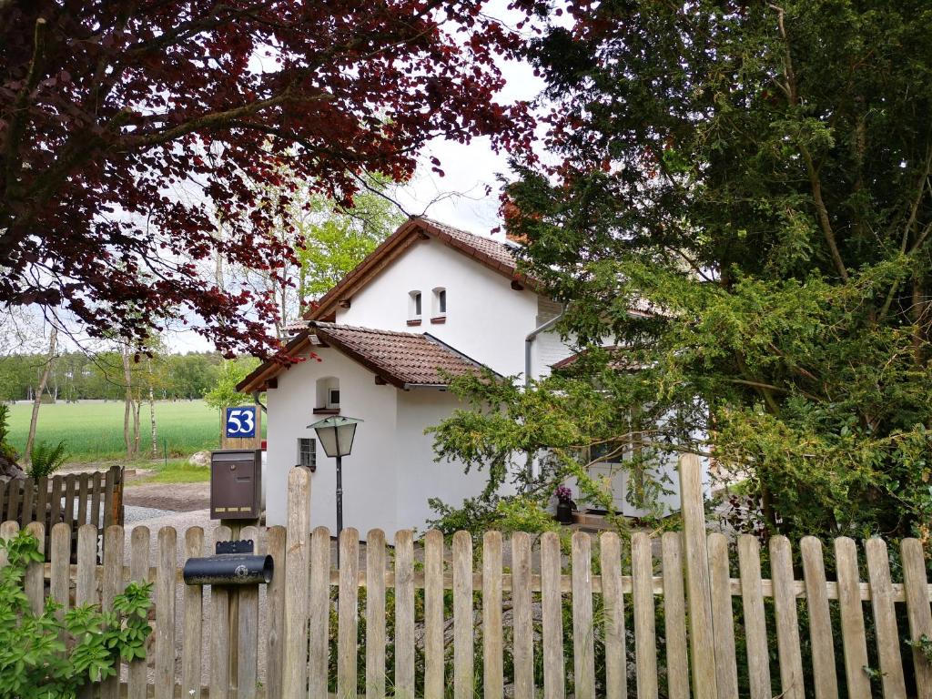 una casa blanca detrás de una valla con un contador de sueldos en Lüttje Heide-Huus, en Soltau