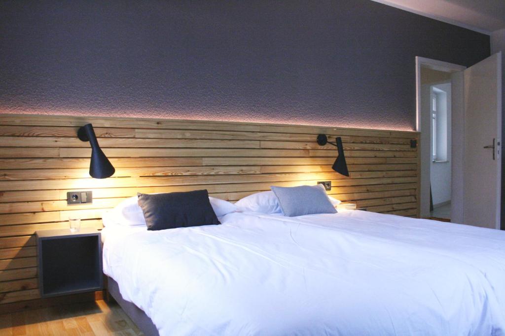 a bedroom with a large white bed with a wooden headboard at FEWO am Markt in Neustadt in Sachsen