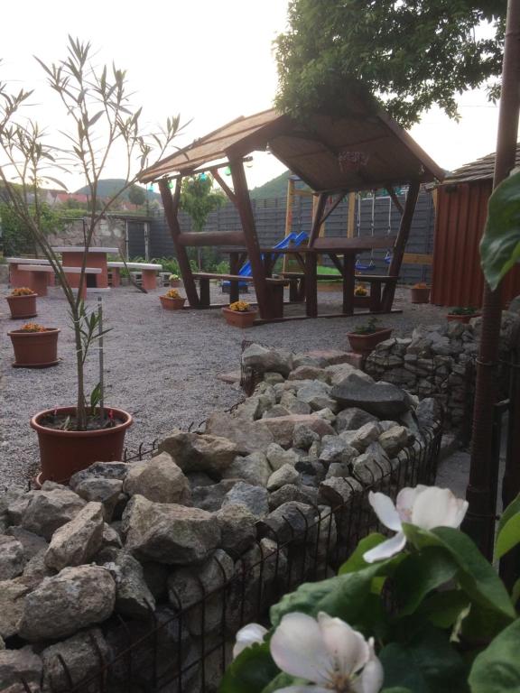 un jardín con una pared de piedra y una mesa de picnic en BORINA VENDÉGHÁZ en Sátoraljaújhely