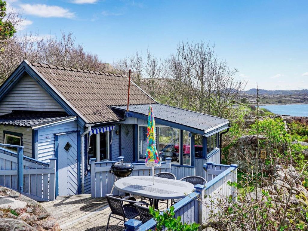 a blue house with a table and chairs on a deck at 4 person holiday home in HAMBURGSUND in Hamburgsund