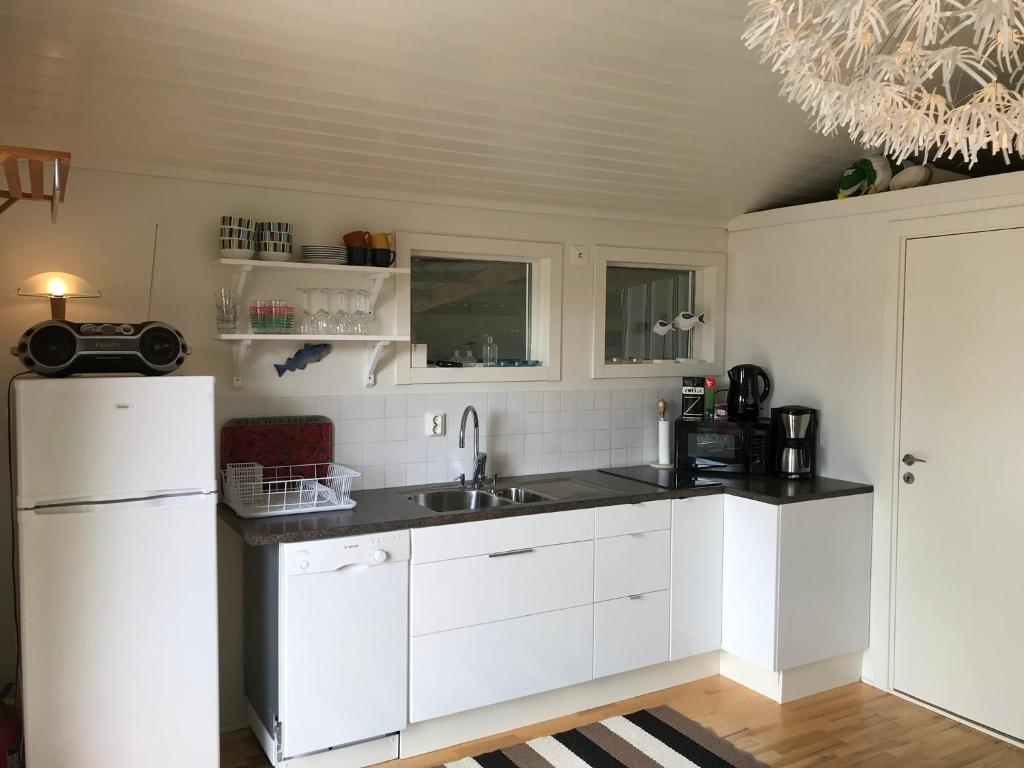 kuchnia z białymi szafkami, zlewem i lodówką w obiekcie Lyckhus w mieście Ljungskile